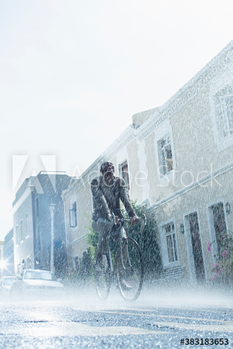Carefree man riding bicycle on rainy street