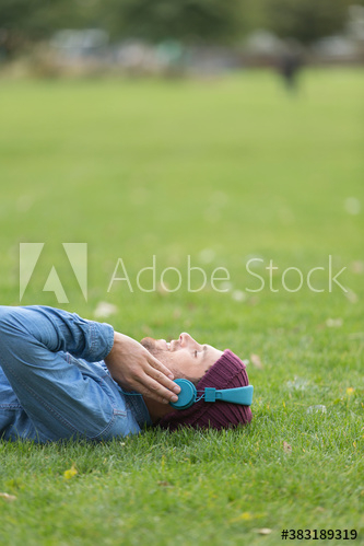 Carefree man with headphones listening to music in grass
