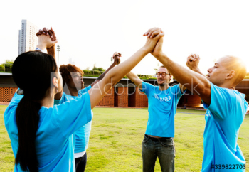 Cheerful volunteers holding hands outdoors Cheerful volunteers holding hands outdoors