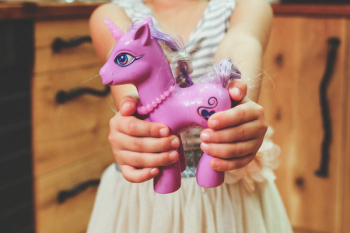 Child holding unicorn toy Child holding unicorn toy