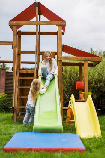Children ride from the children's slide, sisters play together in the garden