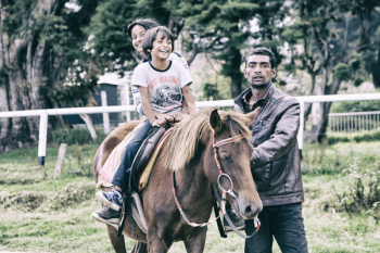 Children Riding Horse With Adult Guiding Children Riding Horse With Adult Guiding