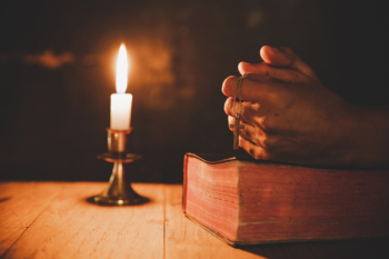 Close up man's hand is praying in the church with lit candle Free Photo
