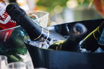 closeup photo of three wine bottles on bucket with ice closeup photo of three wine bottles on bucket with ice