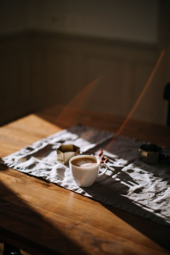 coffee mug on top of tablecloth beside ashtray coffee mug on top of tablecloth beside ashtray