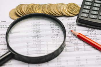 Coins; magnifying glass; pencil and calculator on financial report