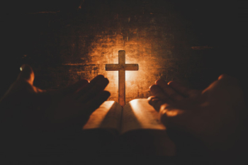 Conceptual image focus on candle light with man hand holding wooden cross on bible and blurred world Free Photo
