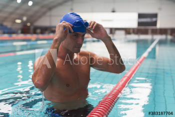 Confident athletic male swimmer preparing in swimming pool