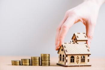 Crop hand putting house near coins Crop hand putting house near coins