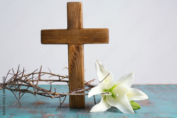 Crown of thorns, wooden cross and white lily on table