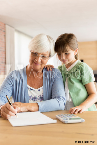 Curious granddaughter watching grandmother budgeting at table Curious granddaughter watching grandmother budgeting at table