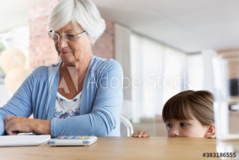 Curious granddaughter watching grandmother paying bills Curious granddaughter watching grandmother paying bills