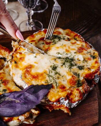 Cutting food with melted cheese and herbs with cutlery. Free Photo Cutting food with melted cheese and herbs with cutlery. Free Photo
