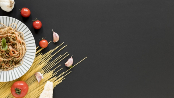 Delicious italian noodles with raw spaghetti; tomato; garlic cloves on black background Free Photo