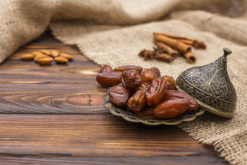 Dried dates fruit on plate with cinnamon and nuts Dried dates fruit on plate with cinnamon and nuts