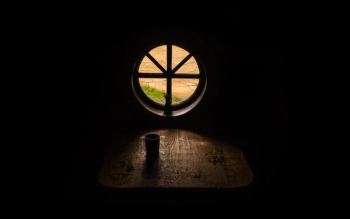 drinking cup on brown wooden table near round attic window drinking cup on brown wooden table near round attic window