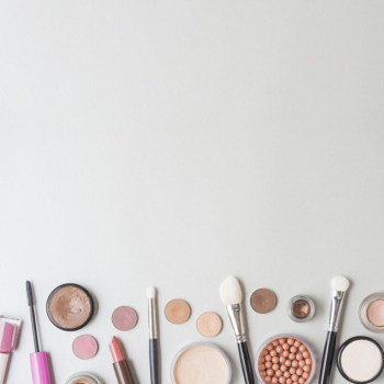 Elevated view of cosmetic products and brushes on white background