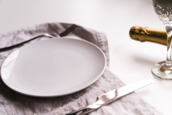 Empty plate with butter knife on napkin near champagne bottle over white background Free Photo