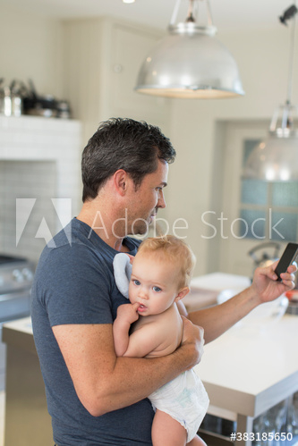 Father holding baby son and using smart phone Father holding baby son and using smart phone