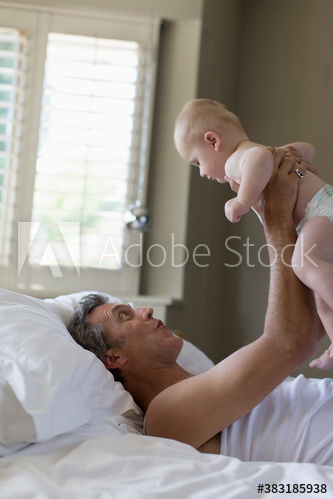 Father holding baby son in bed Father holding baby son in bed