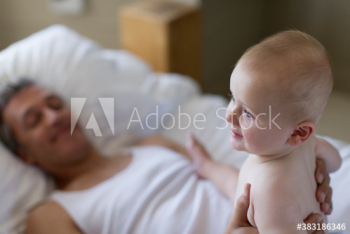Father holding baby son on bed Father holding baby son on bed