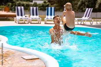 Father laughing while throwing his son into water