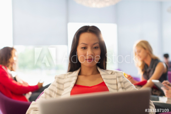 Female college student using laptop in student lounge Female college student using laptop in student lounge