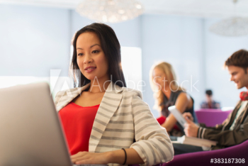 Female college student using laptop in student lounge Female college student using laptop in student lounge