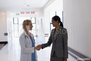 Female doctor and administrator shaking hands in hospital corridor Female doctor and administrator shaking hands in hospital corridor