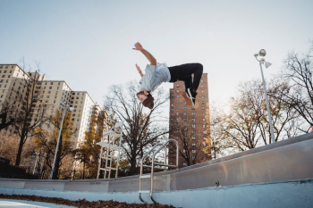 Fit dancer performing trick in air in city