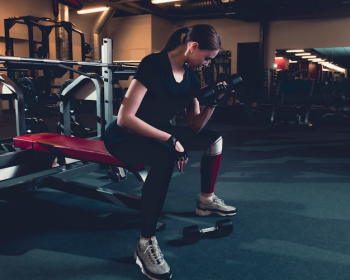 Fit woman doing bicep exercise with dumbbell in fitness center