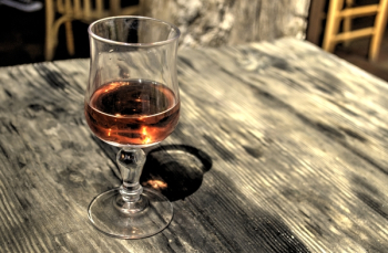Footed Glass Filled With Brown Liquid on Brown Wooden Table