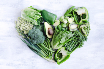 Fresh green vegetables arranged in a heart shape, broccoli, broad beans, capsicum, kiwi, avocado, beans, peas, peppers for healthy living concept