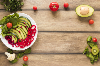 Fresh vegetables and fruits salad in white plate on wooden table