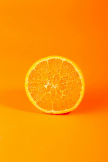 Freshly Sliced Orange on Vibrant Orange Background Freshly Sliced Orange on Vibrant Orange Background