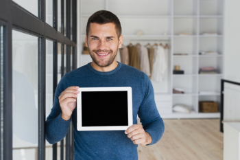 Front view man with tablet showing it to camera Free Photo