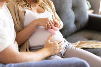 Future mother applying baby girl shoes to belly Free Photo