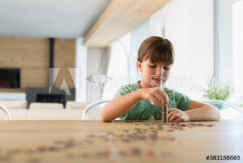 Girl counting and stacking coins at dining table Girl counting and stacking coins at dining table