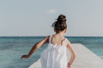 girl running on dock under white sky girl running on dock under white sky