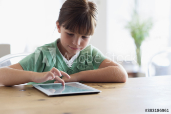 Girl using digital tablet at dining table Girl using digital tablet at dining table
