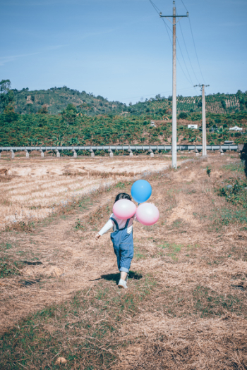 Girl Walking Holding Pink And Blue Latex Balloons Girl Walking Holding Pink And Blue Latex Balloons