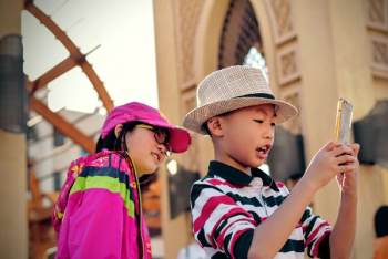 girl watching behind boy holding smartphone girl watching behind boy holding smartphone