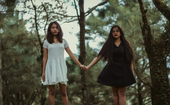 Girl Wearing White Dress Holding Hands With Girl Wearing Black Dress Girl Wearing White Dress Holding Hands With Girl Wearing Black Dress
