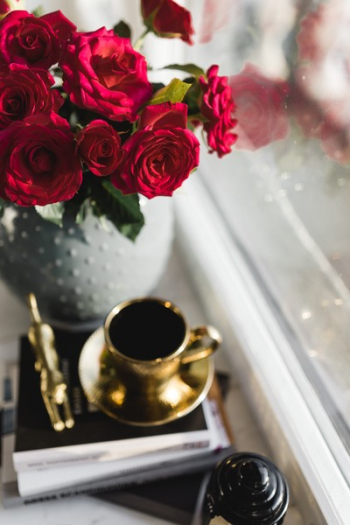 Gold cup of coffee and red roses bouqet Gold cup of coffee and red roses bouqet