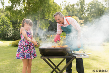 Grandfather and granddaughter barbecuing in summer backyard Grandfather and granddaughter barbecuing in summer backyard