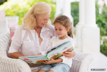 Grandmother and granddaughter reading book on patio Grandmother and granddaughter reading book on patio