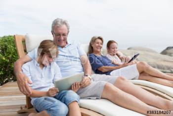 Grandparents and grandkids using digital tablets on lounge chairs Grandparents and grandkids using digital tablets on lounge chairs