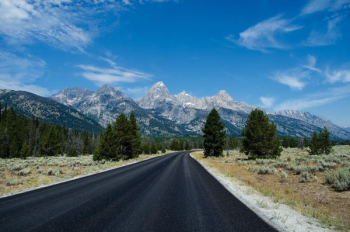 gray asphalt road under blue sunny sky gray asphalt road under blue sunny sky