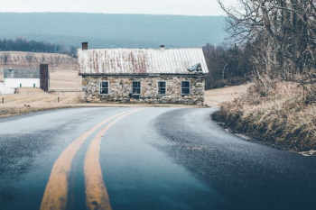 gray brick house beside road under cloudy sky gray brick house beside road under cloudy sky