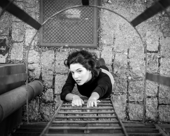 Gray scale photo of a woman about to climb the fire escape ladder Gray scale photo of a woman about to climb the fire escape ladder